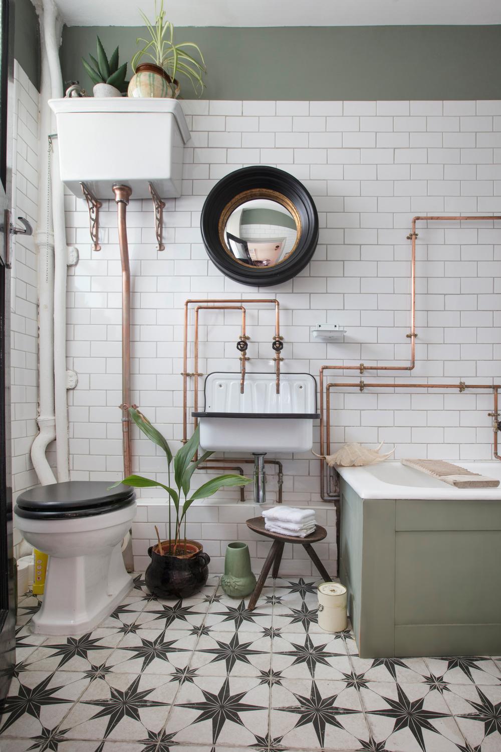 An industrial bathroom with white subway tiles, black-and-white patterned flooring, and vintage accents.
