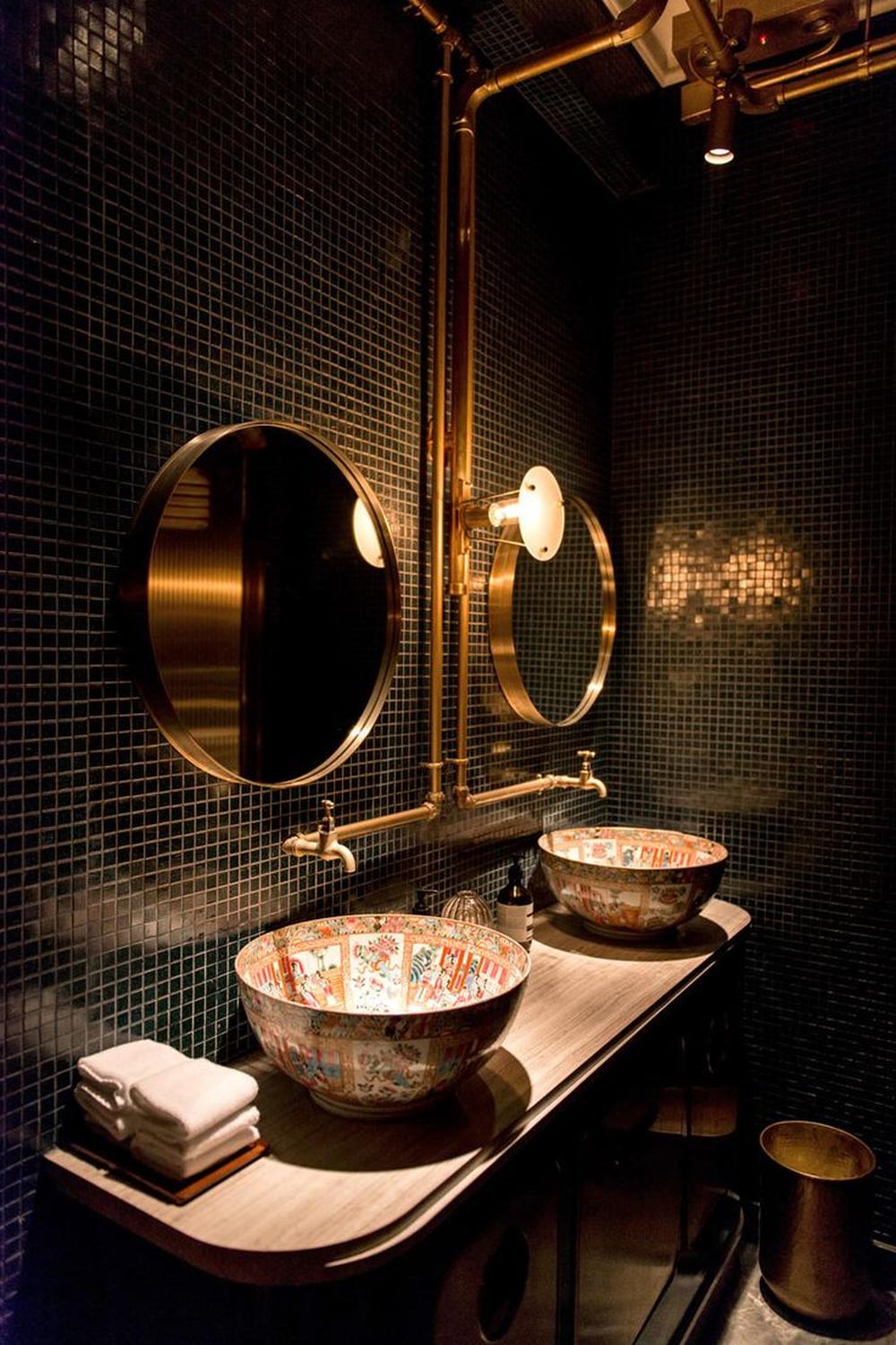 Baño industrial sofisticado con tonos oscuros y detalles artísticos
