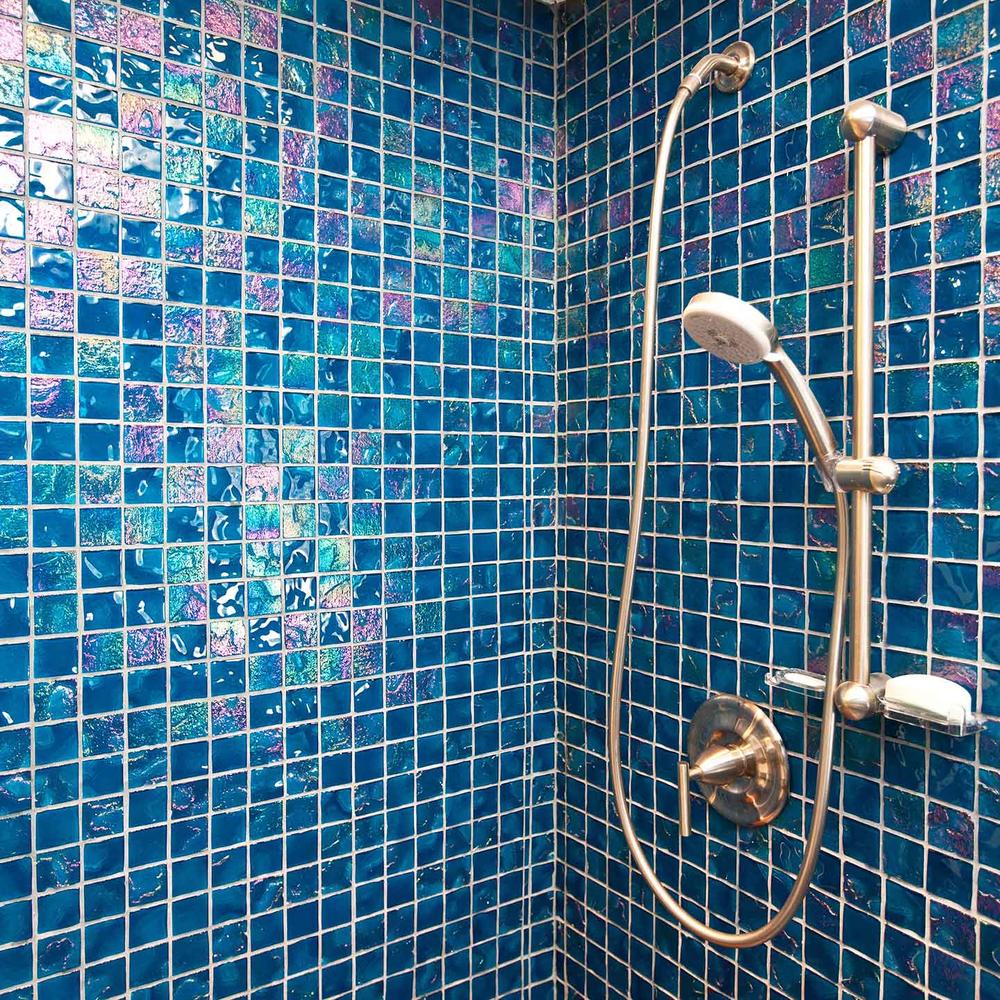 Espacio de ducha moderno con azulejos iridiscentes en tonalidades de azul y verde.