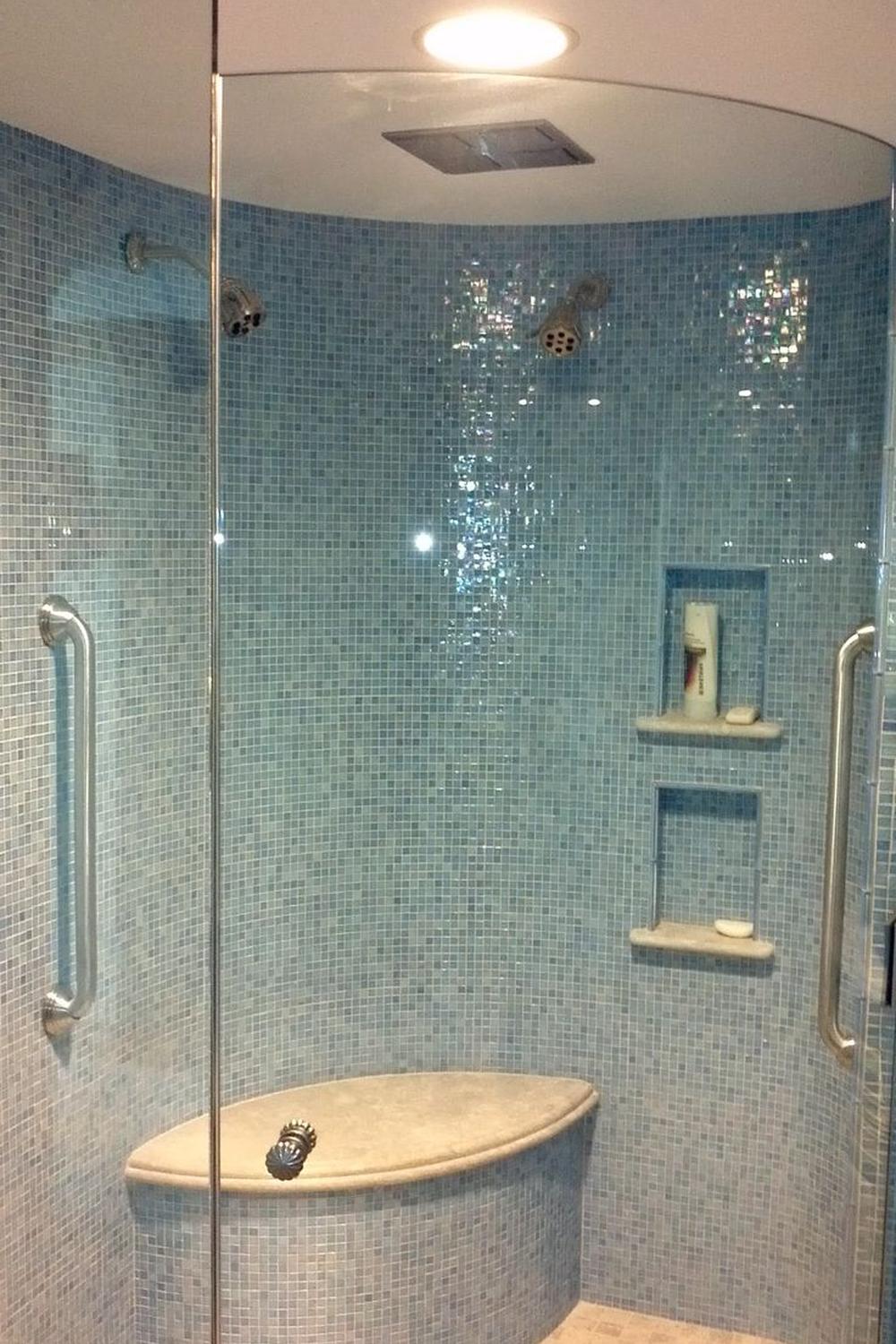 Elegante área de ducha con azulejos iridiscentes en tonalidades azules.