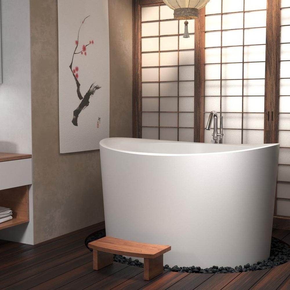 Baño japonés con bañera freestanding blanca y piedras oscuras