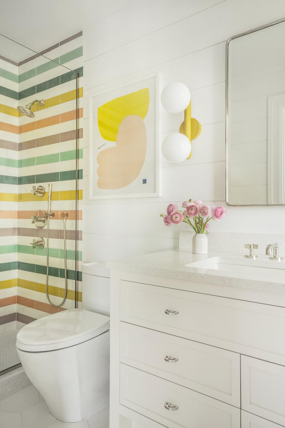 A lively kids' bathroom with colorful tiled shower walls and whimsical accents.