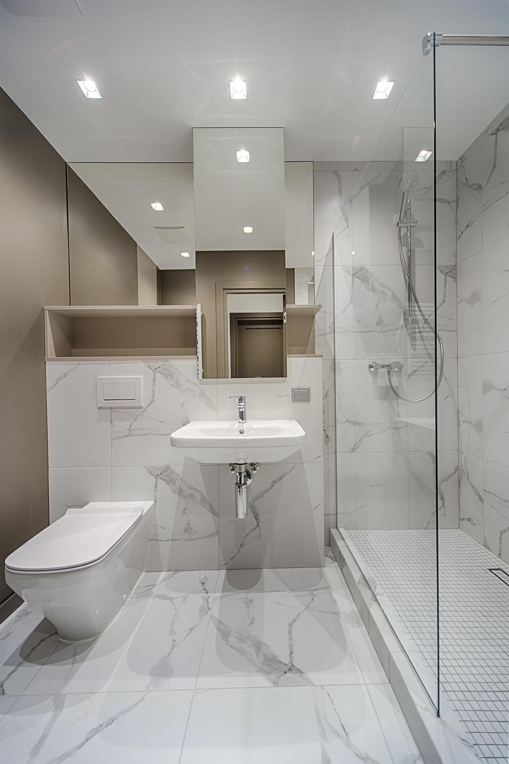 A modern Korean bathroom characterized by an elegant color palette of whites and light beige with large format tiles and sleek fixtures.