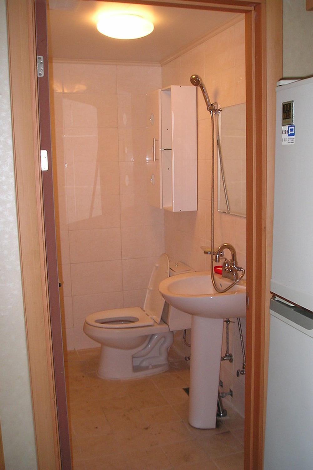 A compact Korean bathroom with a clever layout, showcasing modern fixtures and efficient use of space with light-colored tiles.