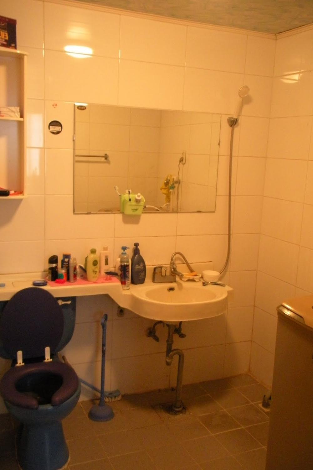 A compact Korean bathroom featuring bright ceramic tiles and stylish sanitary fixtures, emphasizing a practical and aesthetic appeal.