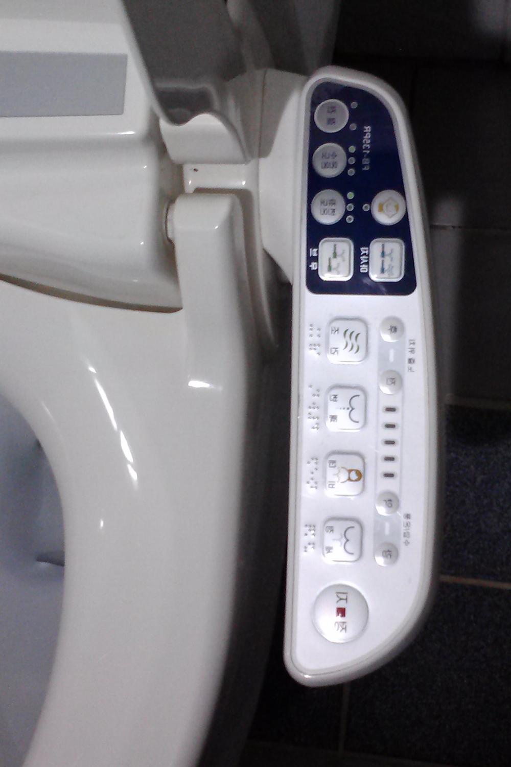 A modern toilet equipped with high-tech features and sleek aesthetics in a compact Korean bathroom.