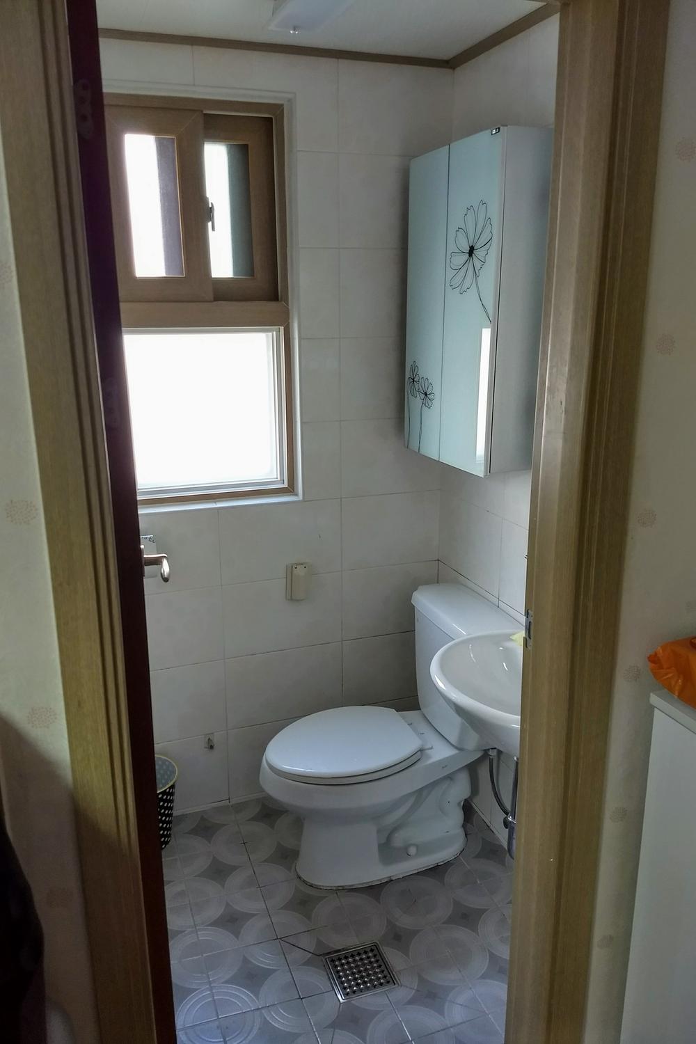A compact Korean bathroom that emphasizes practical design with efficient use of space and decorative elements.
