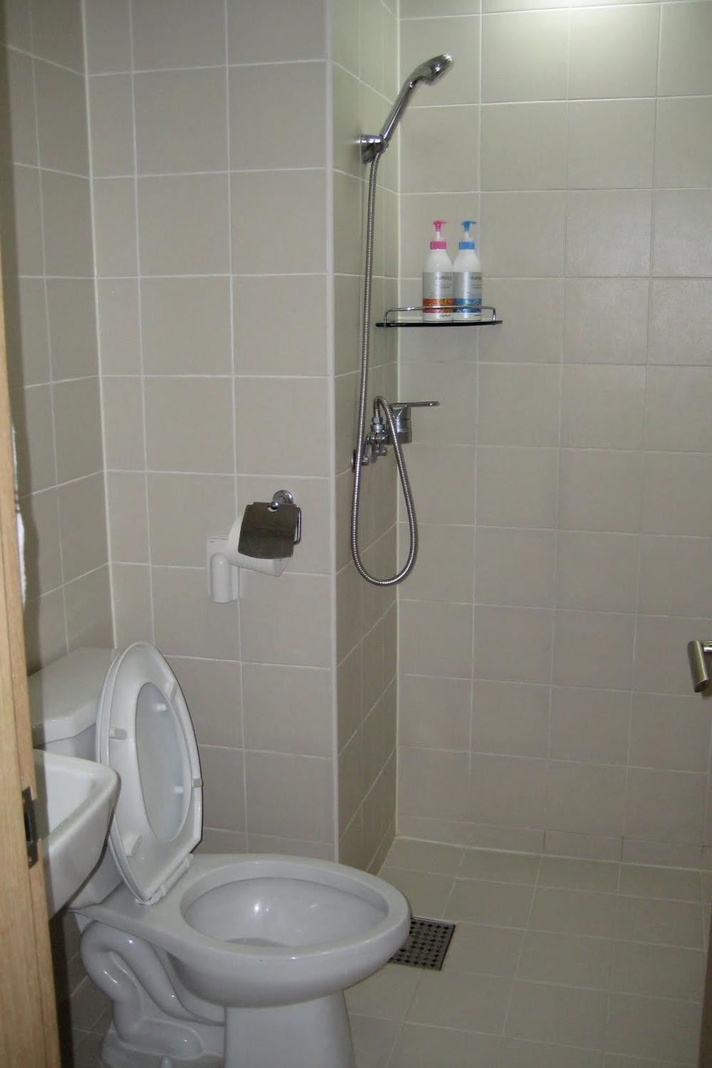 A compact Korean bathroom featuring a stylish toilet and simple shower area with efficient storage.