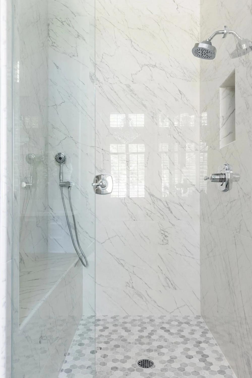 Modern bathroom shower features large format white tiles with elegant fixtures
