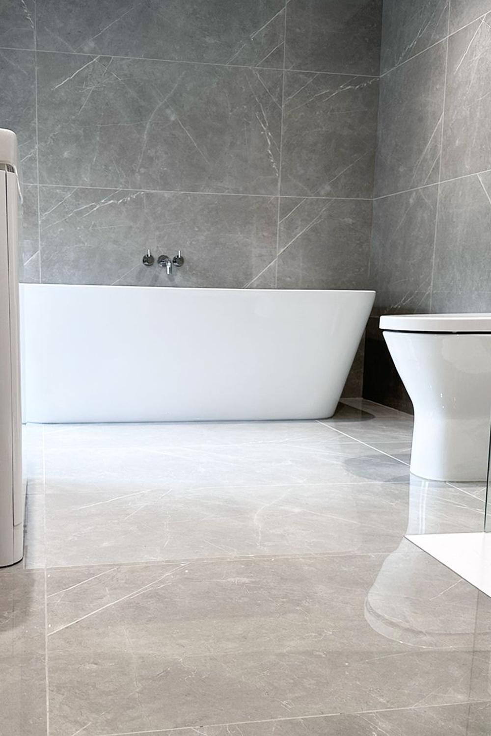 Modern bathroom with glossy gray tiles and freestanding bathtub