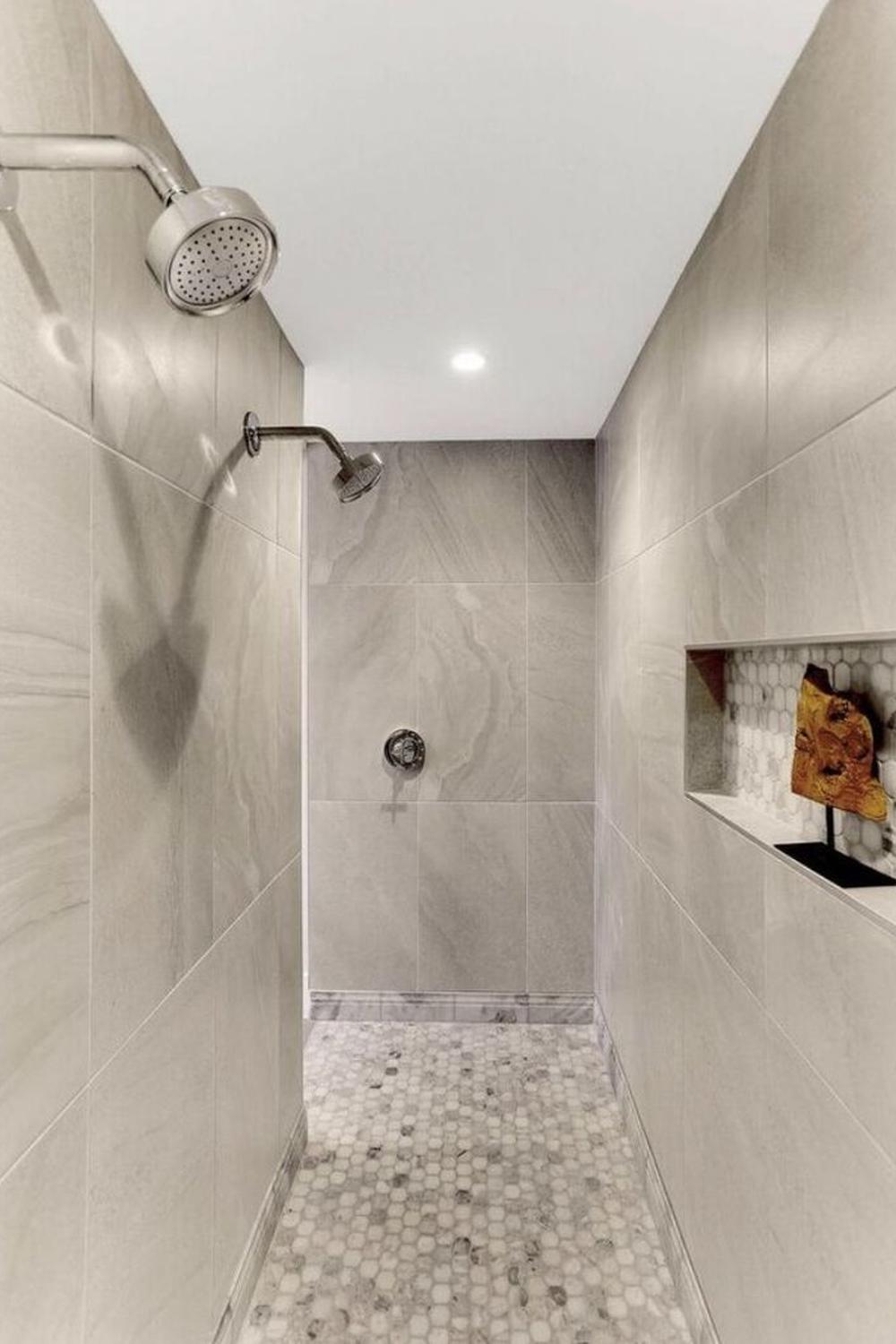 Modern shower space featuring gray tiles and white hexagonal flooring