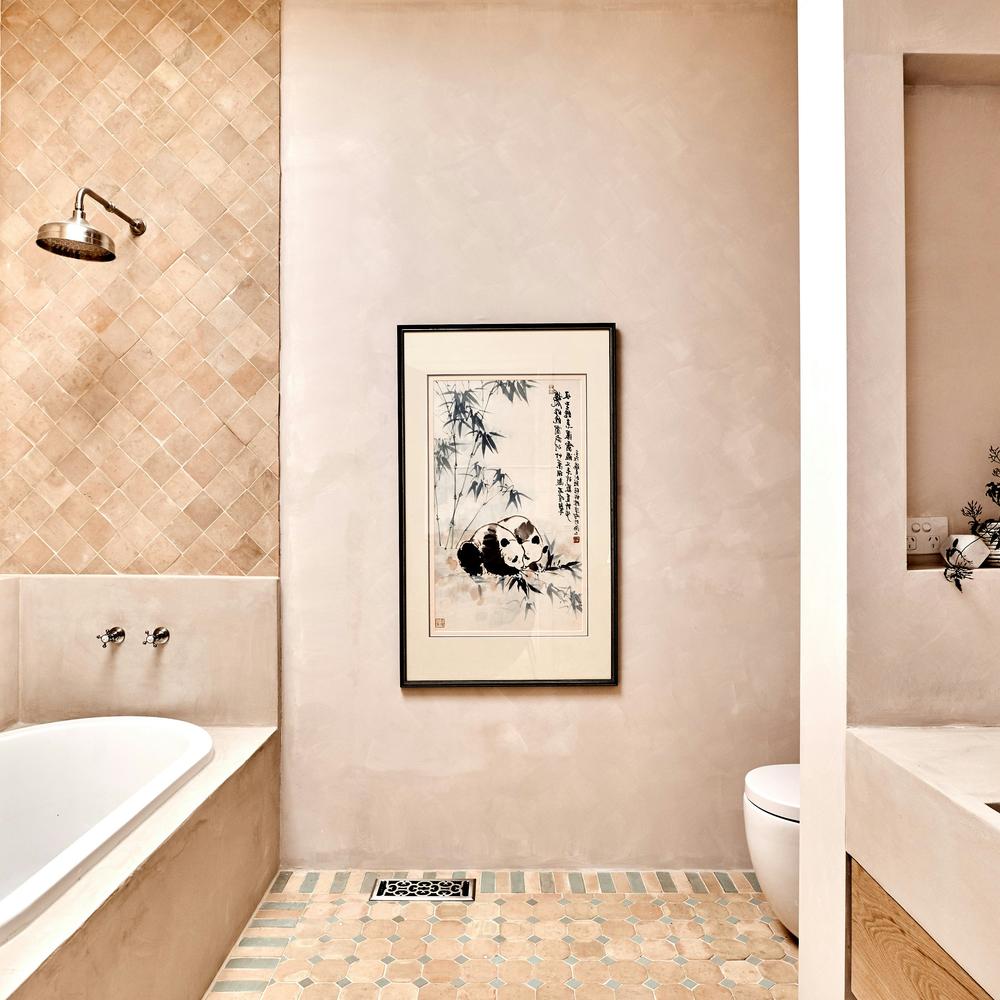 A stylish bathroom characterized by sophisticated limewash aesthetic with textured walls and mosaic tiles.