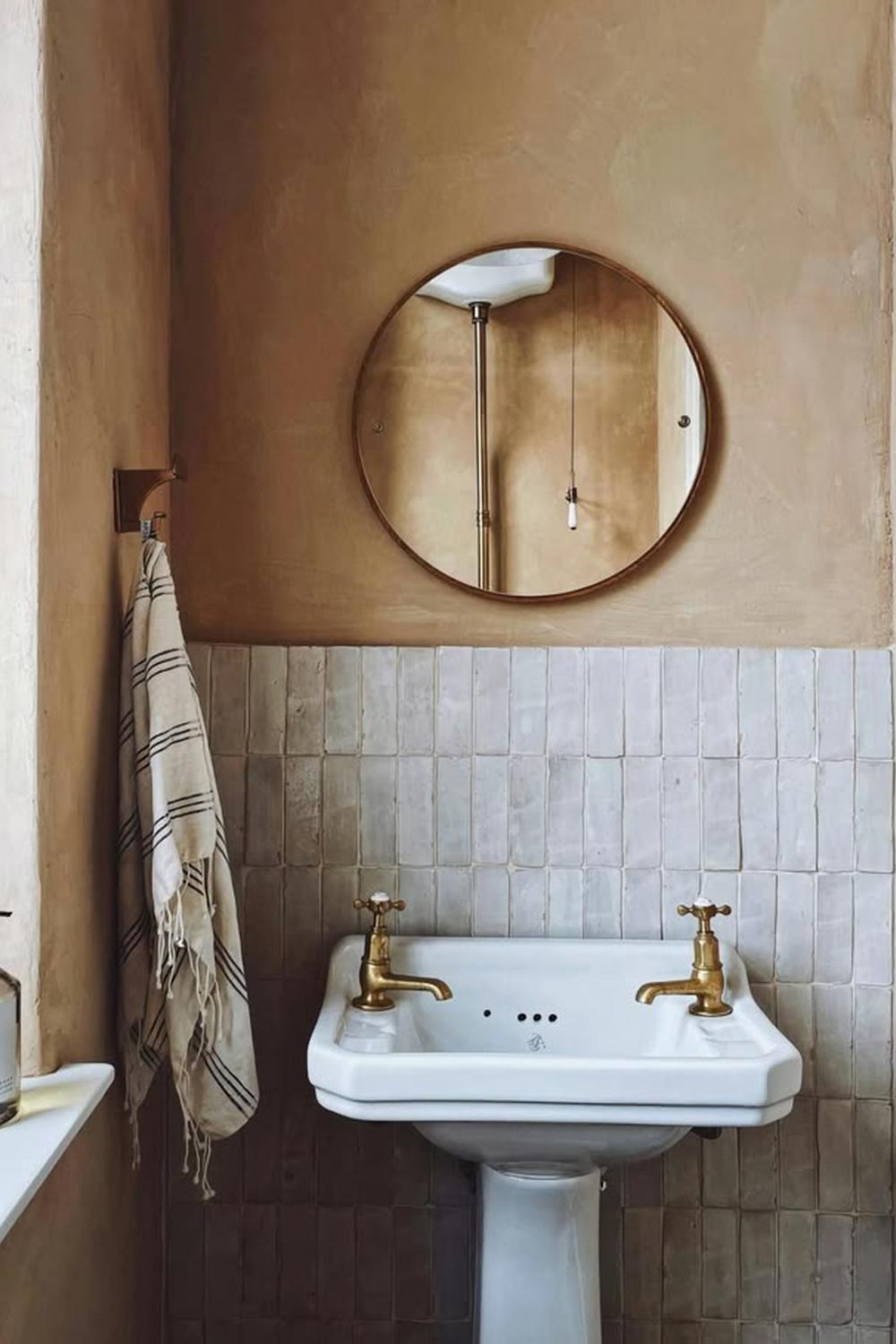 A minimalistic bathroom featuring warm beige limewash walls and a vintage-inspired sink.