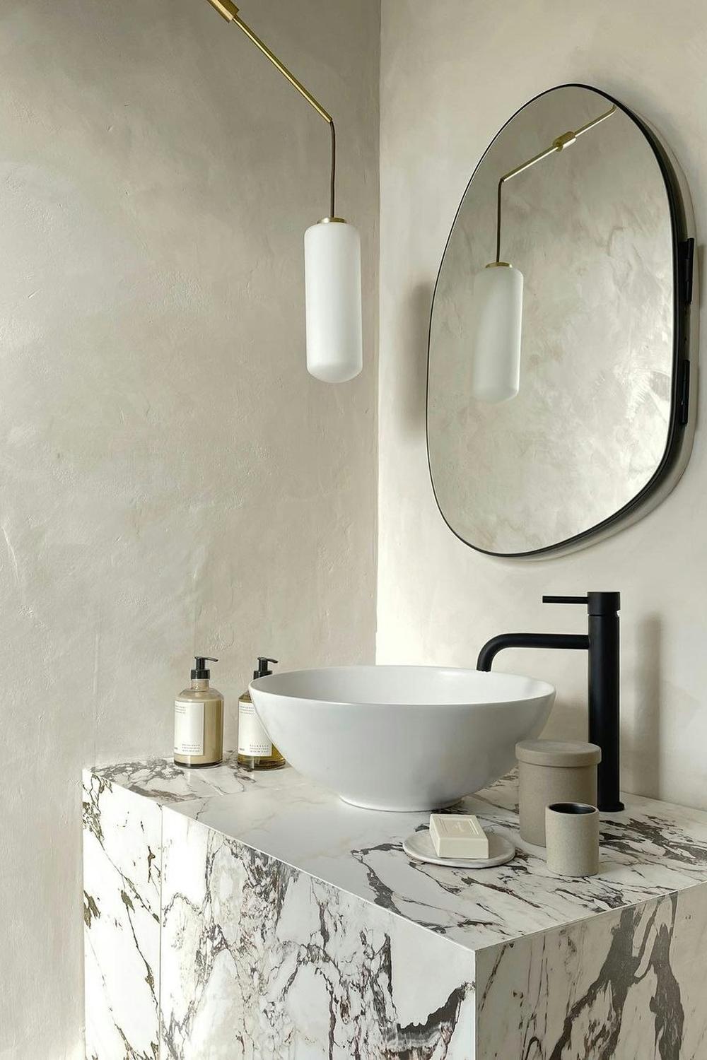 A modern bathroom with a marble vanity and minimalist limewash wall treatment.