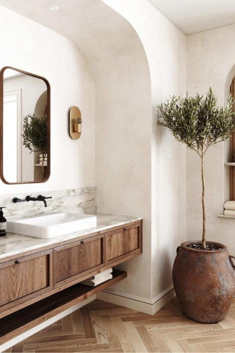 A bright bathroom with an emphasis on a wooden vanity and limewash textures.