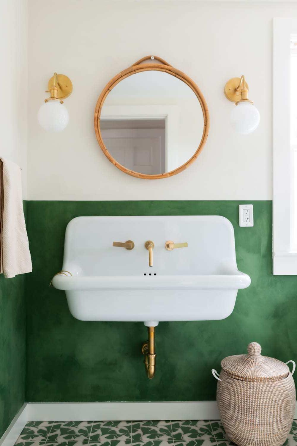 A stylish bathroom with earthy tones, featuring a deep green limewash finish on the lower wall.