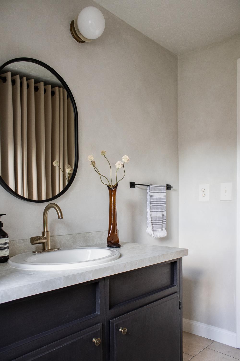 A chic minimalistic bathroom with gray limewash walls and stylish accents.