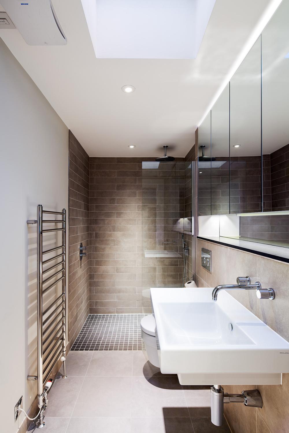 A sleek narrow bathroom characterized by soft beige and gray tones.