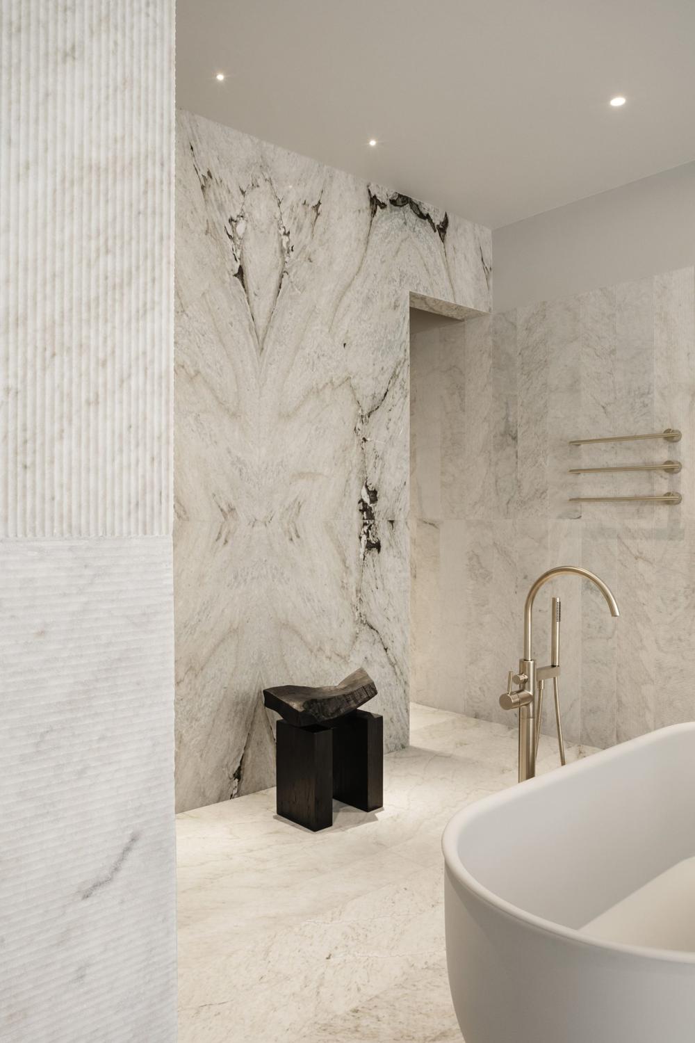 A luxurious bathroom showcasing white marble walls with dark veining and a modern freestanding bathtub.