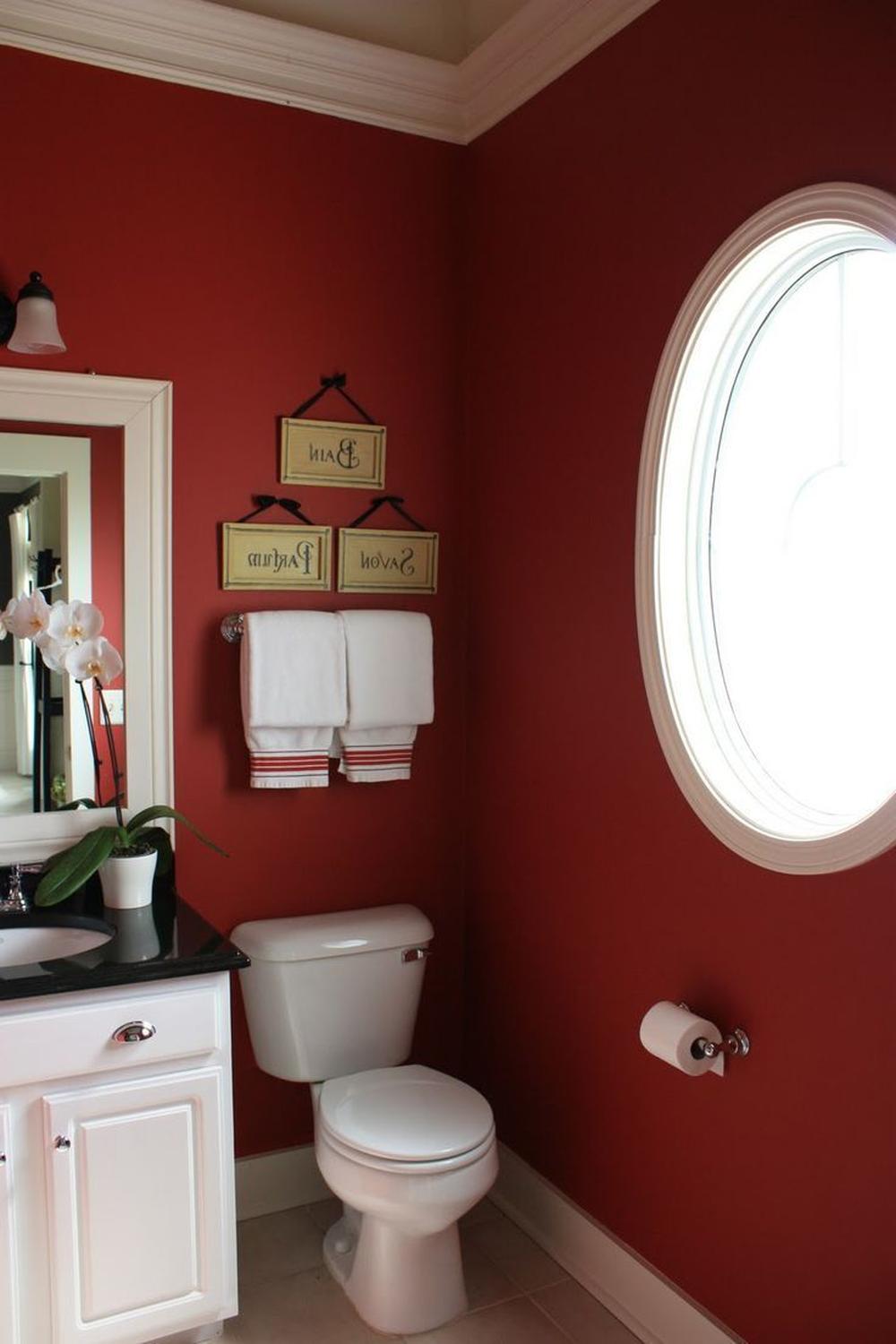 A small, stylish bathroom featuring rich maroon walls, a white-framed mirror, and elegant decor elements.