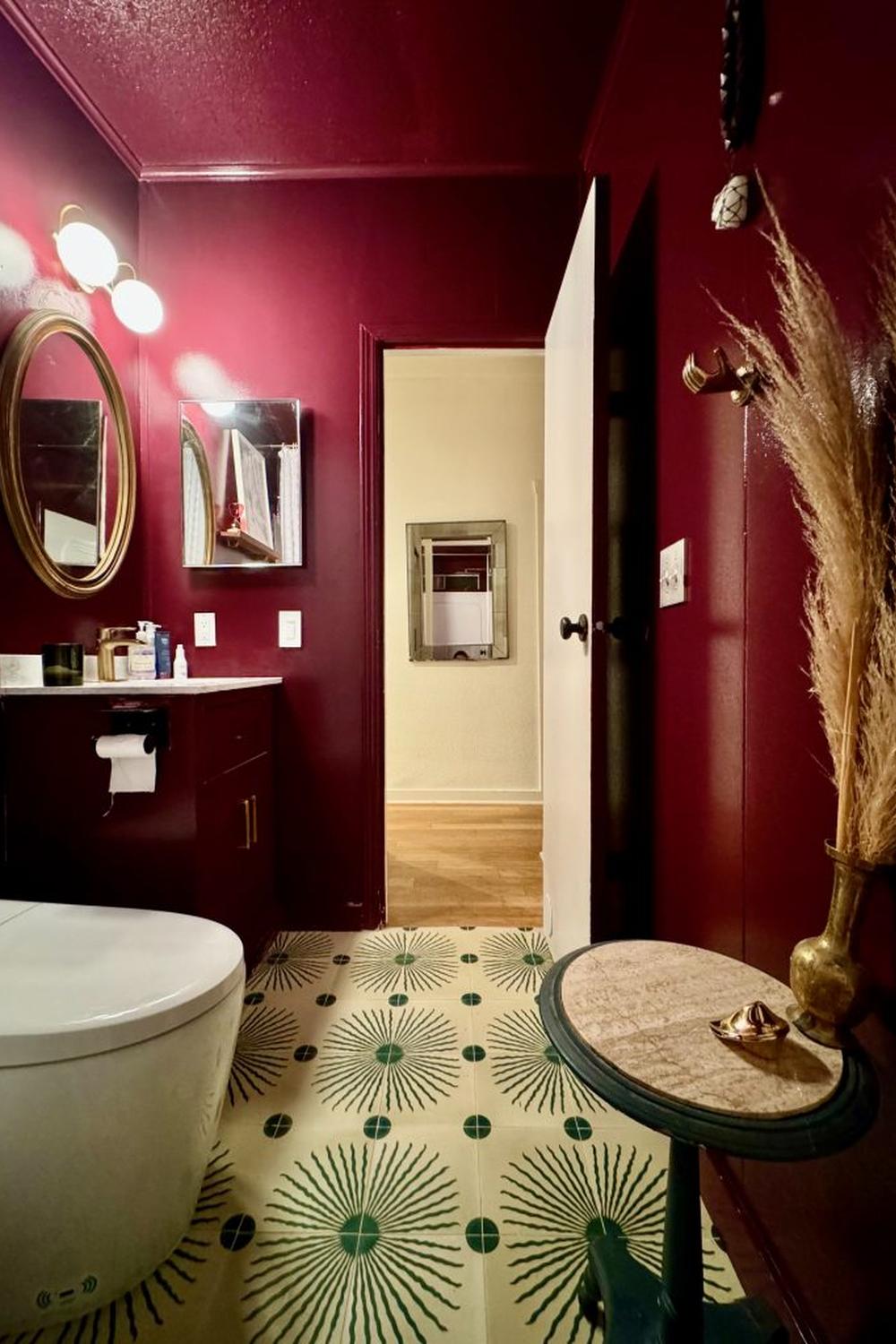 Sophisticated bathroom enhanced by maroon walls and a unique light fixture providing a warm glow.