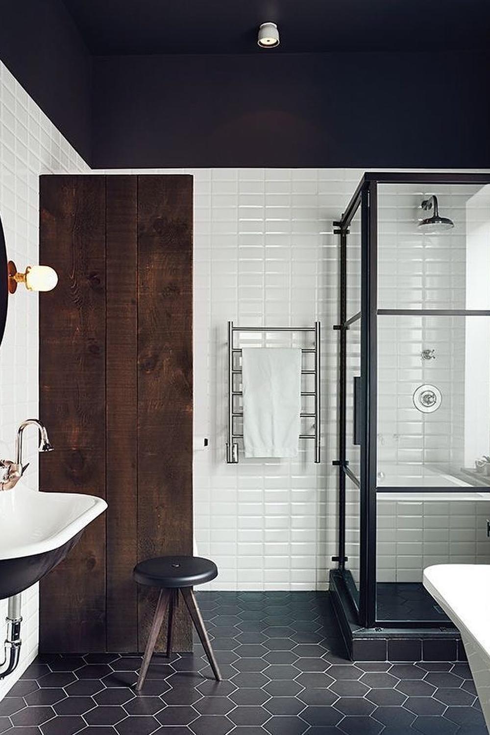 An industrial-style masculine bathroom with dark ceiling and white tiled walls.