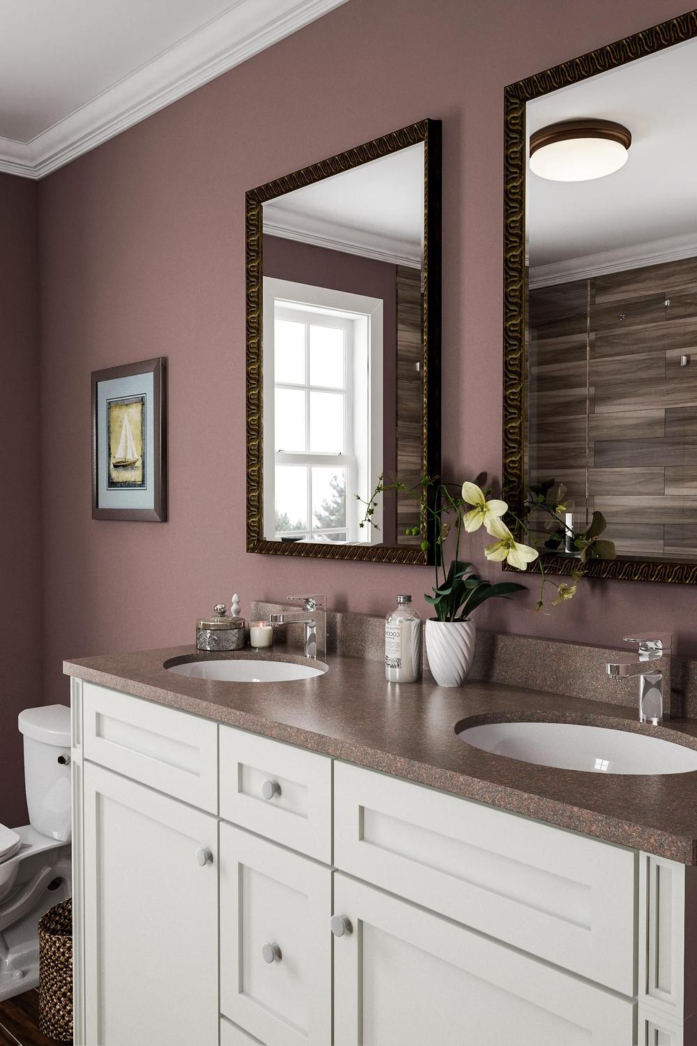 Elegant dual sink vanity with soft mauve walls and a textured brown stone countertop.