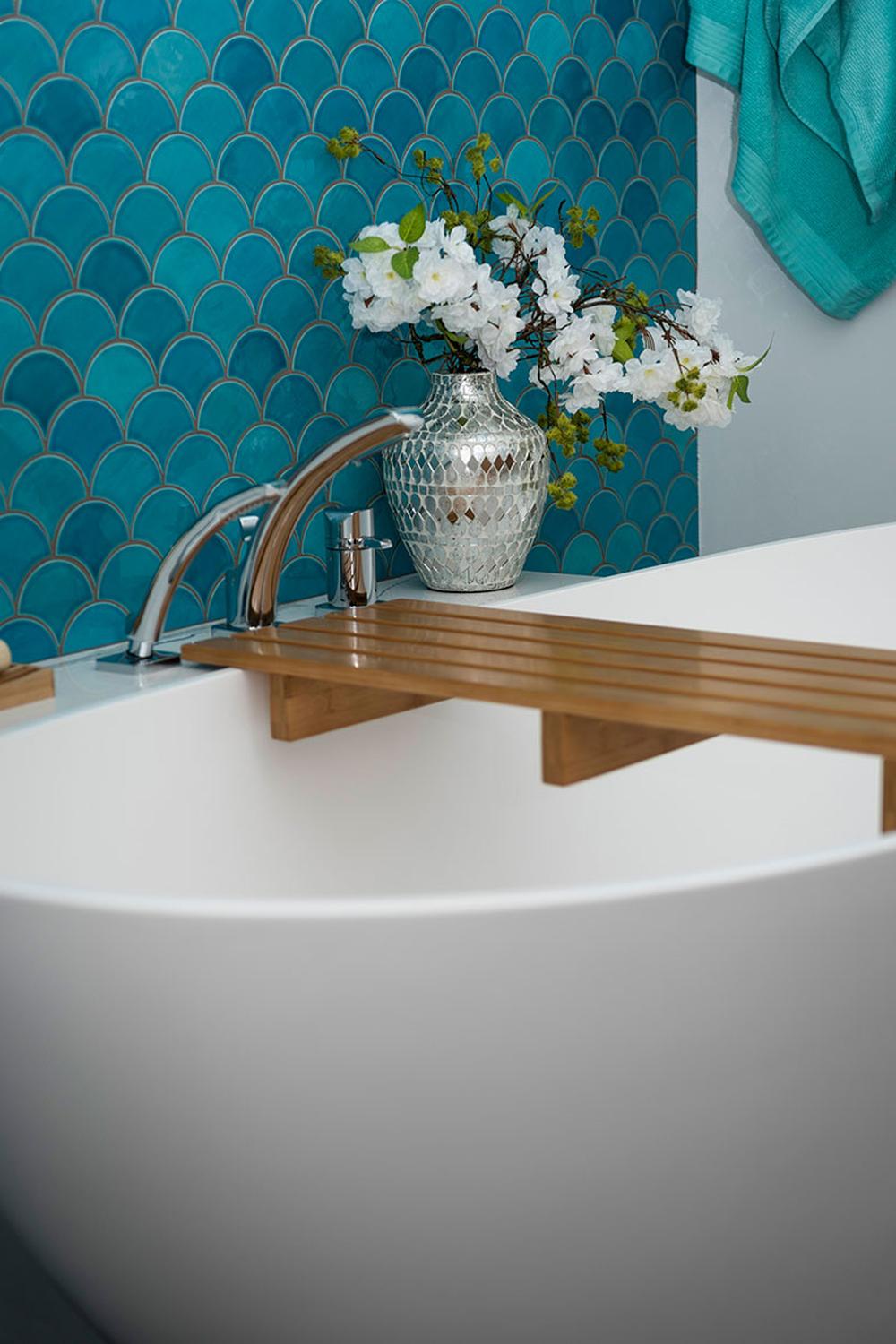 Stylish bathroom with turquoise mermaid scale tile wall, freestanding bathtub, and decorative elements