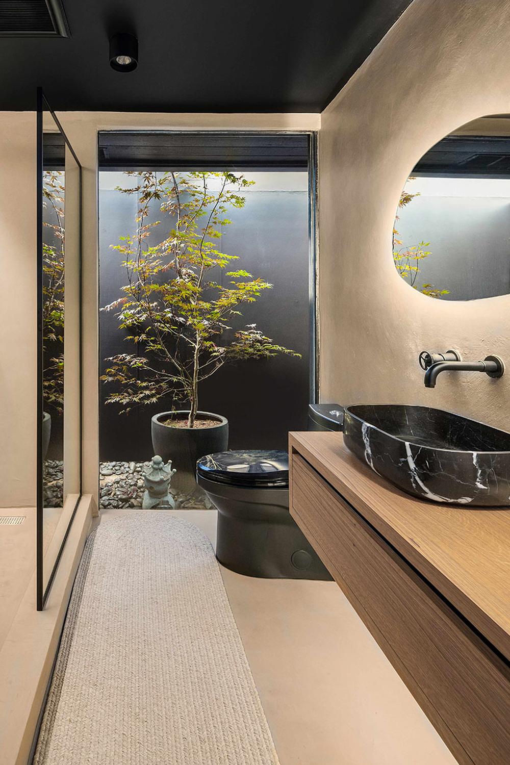 A compact modern bathroom featuring micro cement finishes and a floor-to-ceiling window.