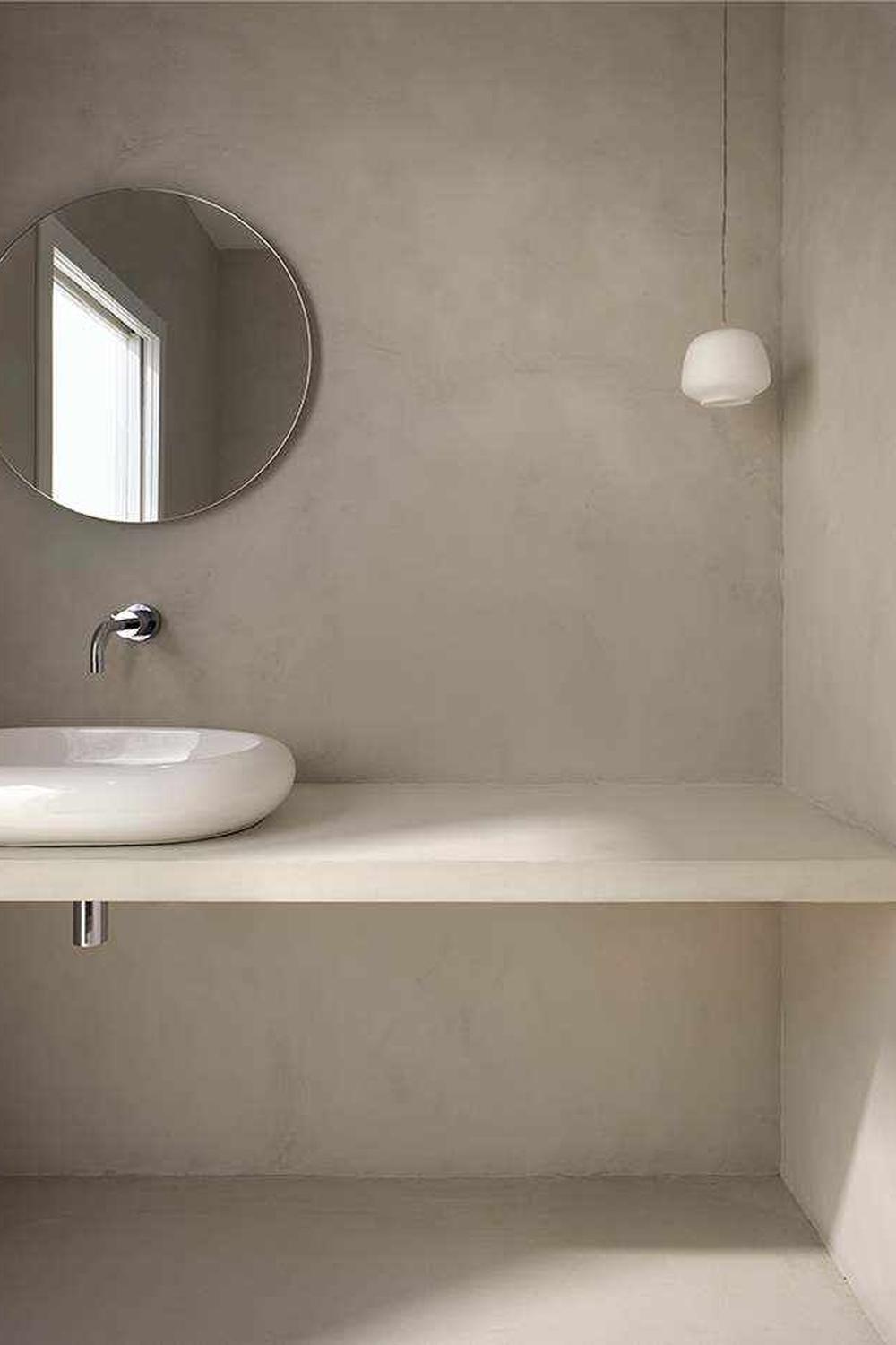 A minimalist bathroom with a floating vanity and oval basin, showcasing a bright atmosphere provided by natural light and simple decor.