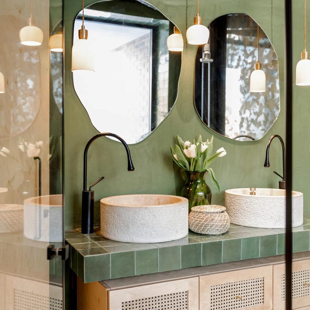 Bathroom highlights twin sinks atop mint green tiles, showcasing a modern design.