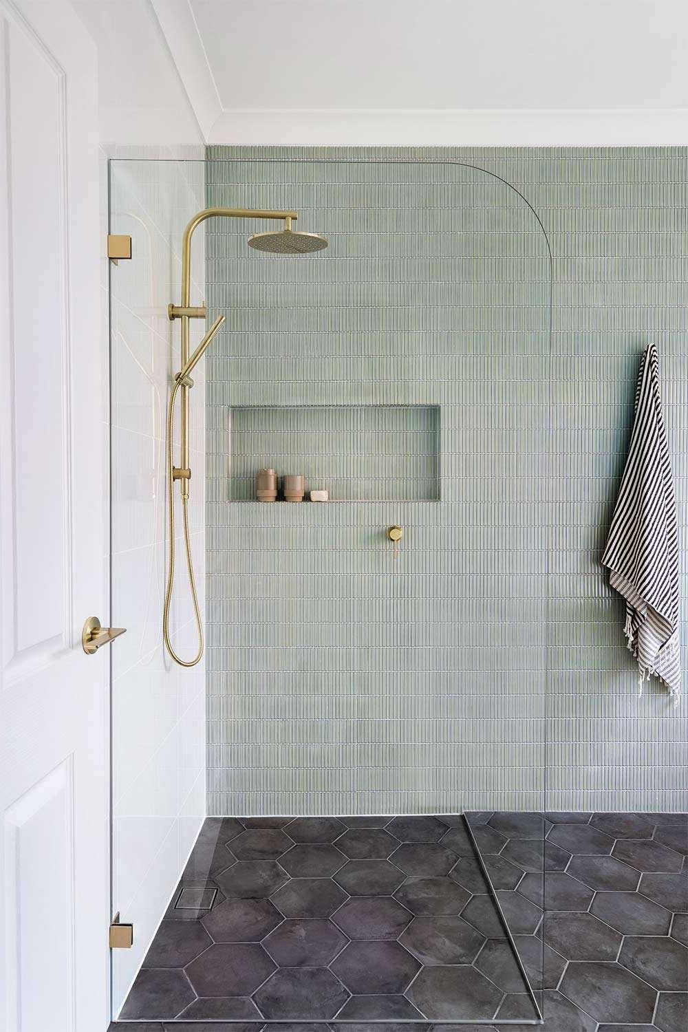 Contemporary bathroom with textured mint green wall tiles and brass fixtures