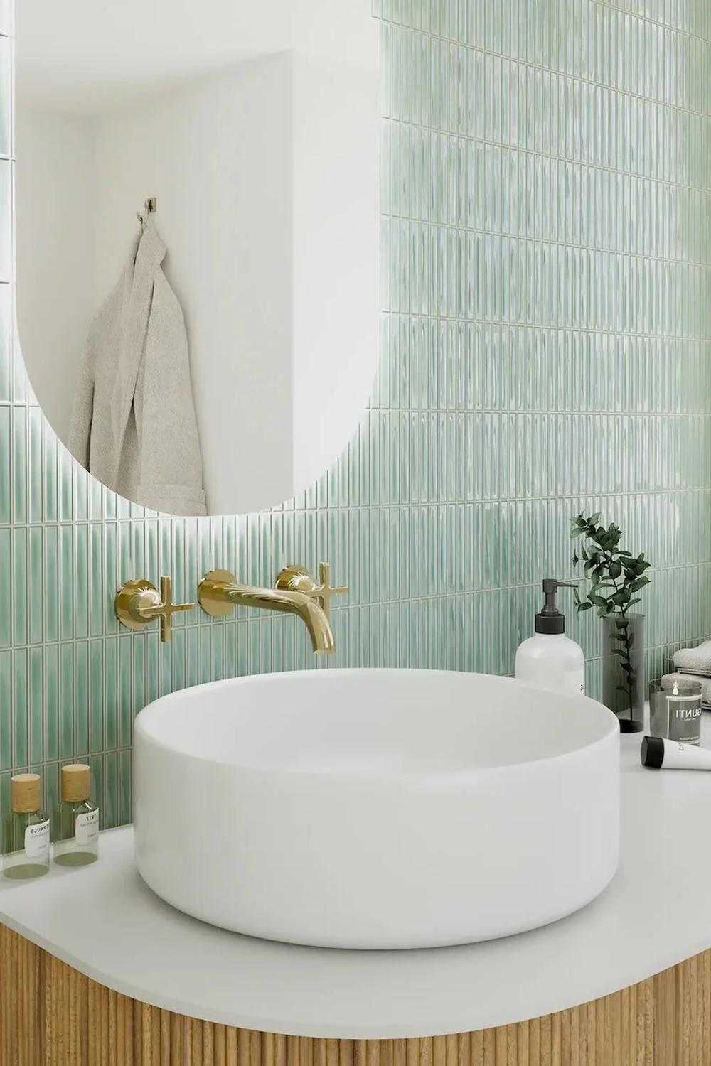 Stylish bathroom featuring a circular vanity sink with gold fixtures