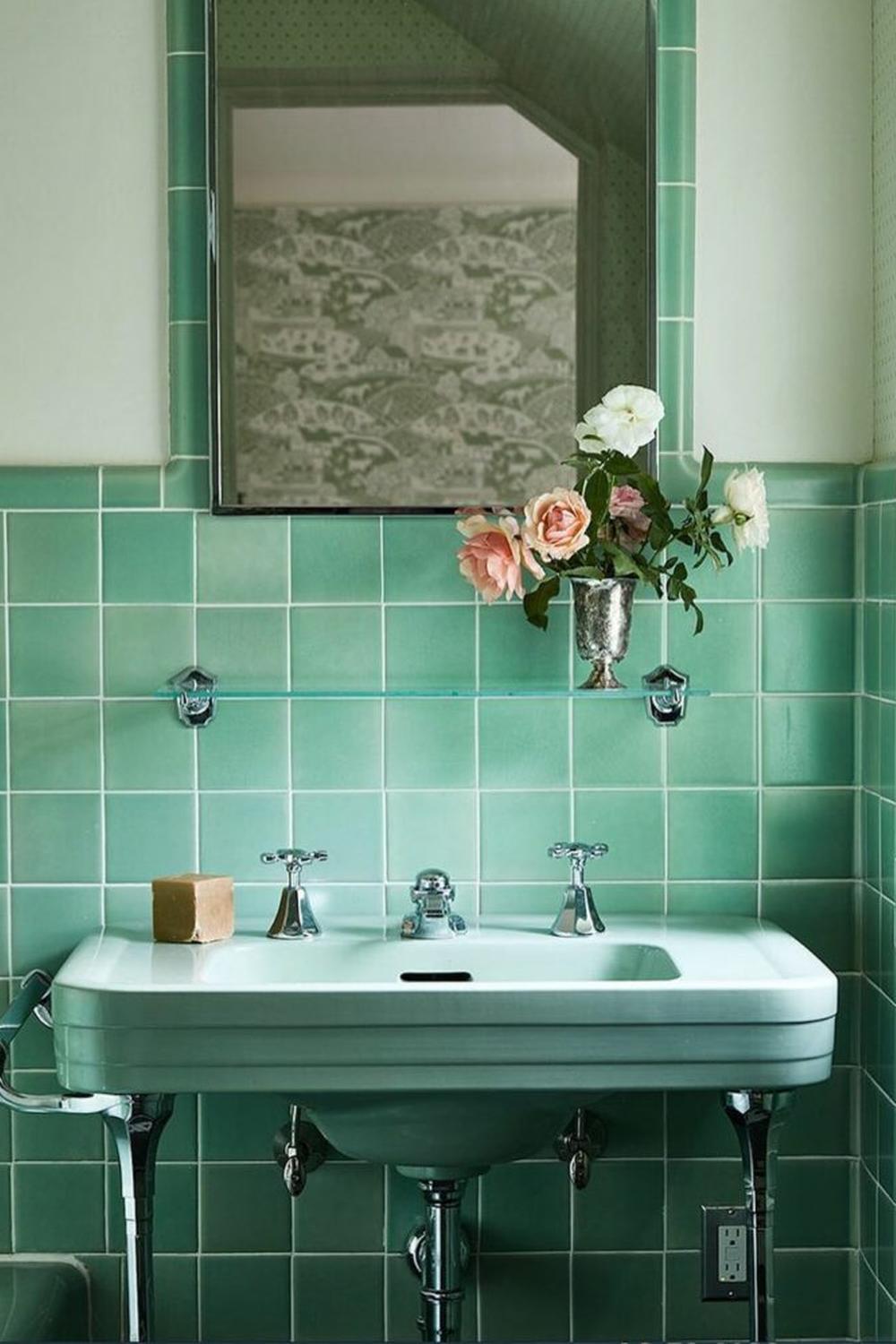 Vintage-style bathroom with mint green tiles and decorative floral arrangement