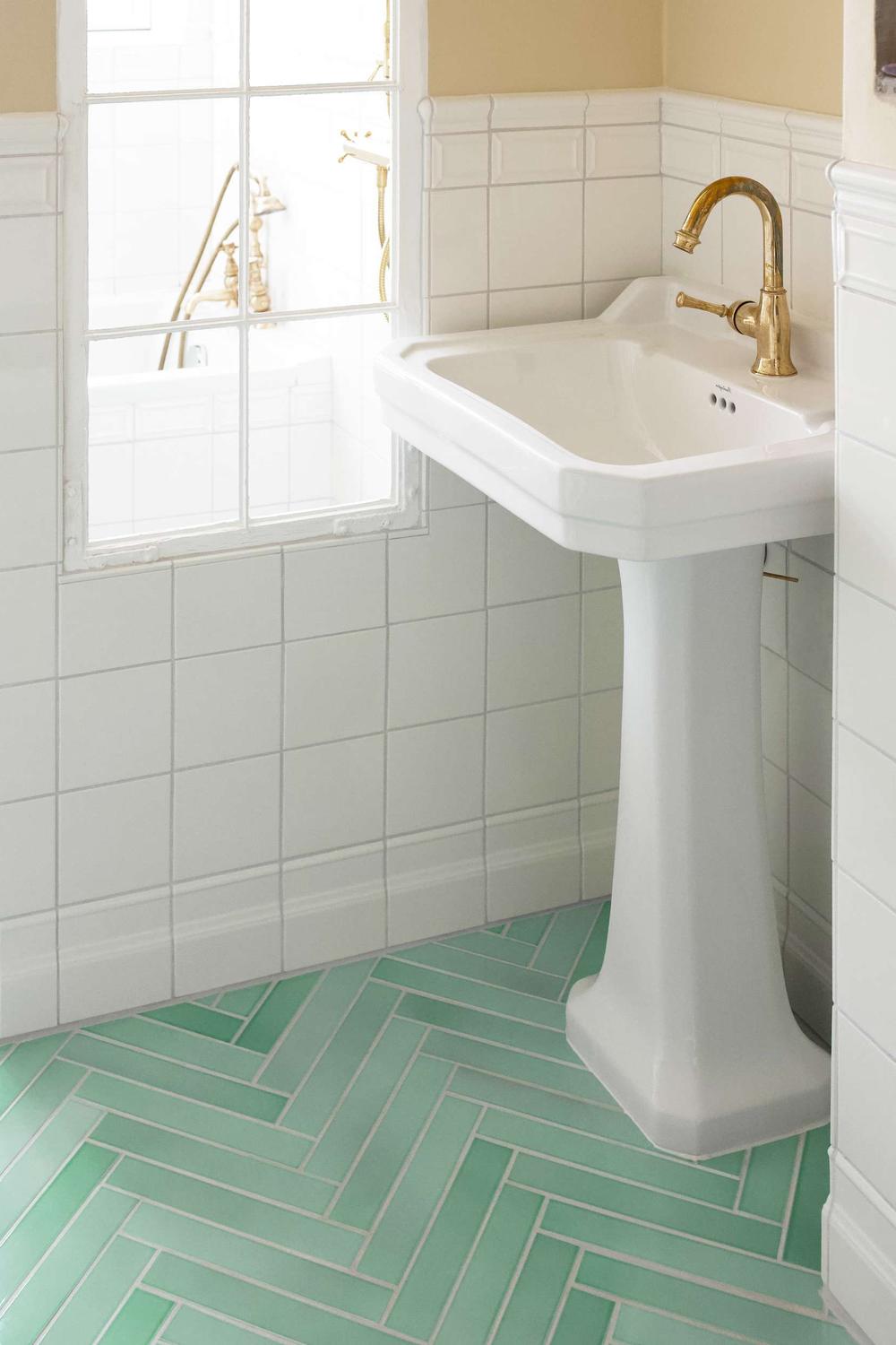 Bathroom featuring mint green herringbone tile flooring and classic design elements