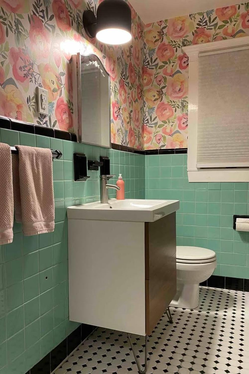 Vibrant bathroom featuring mint green tiles with colorful floral wallpaper accents