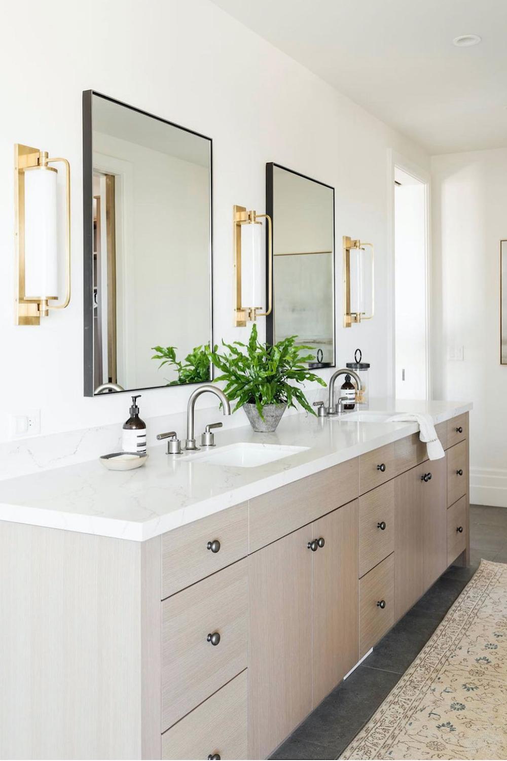 Baño moderno que combina metales y elementos naturales con acabados cálidos.