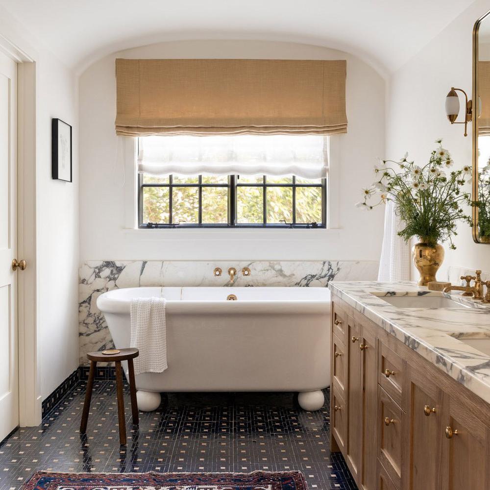Modern farmhouse bathroom featuring a white freestanding bathtub with clawfoot design.