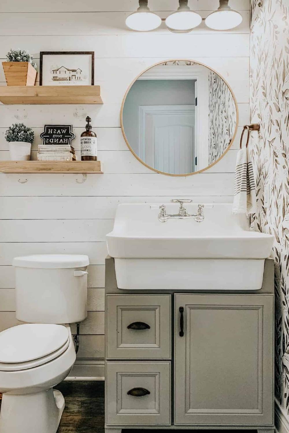 Inviting modern farmhouse bathroom with metal light fixtures and wooden shelves.