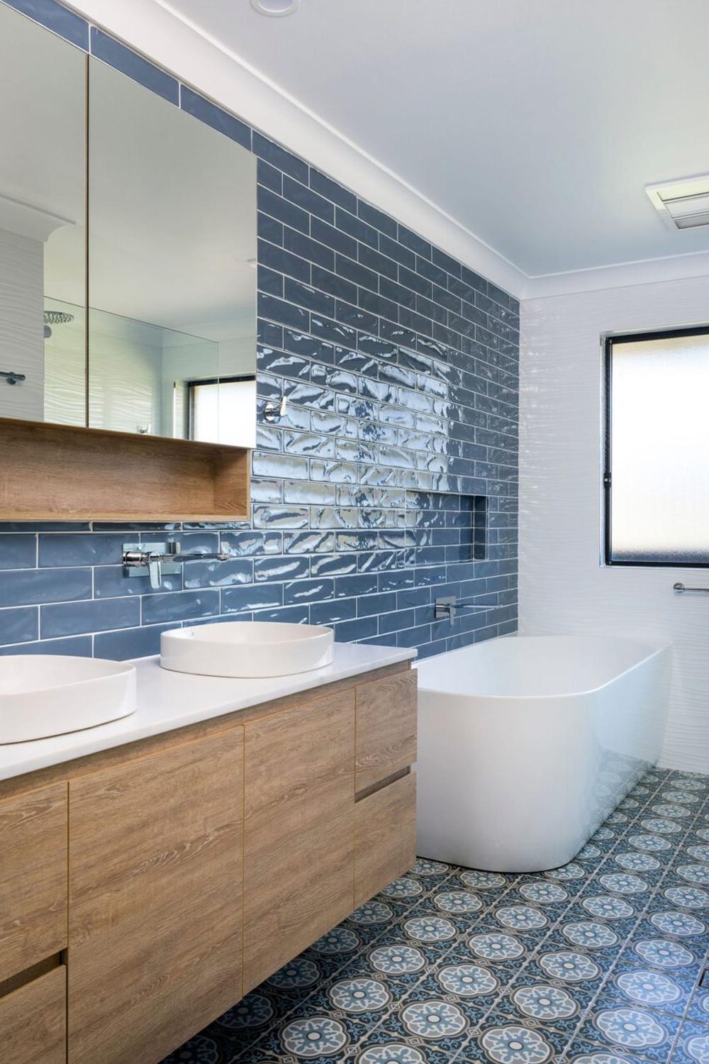 A charming blue and white modern boho bathroom featuring patterned tiles and a freestanding bathtub.
