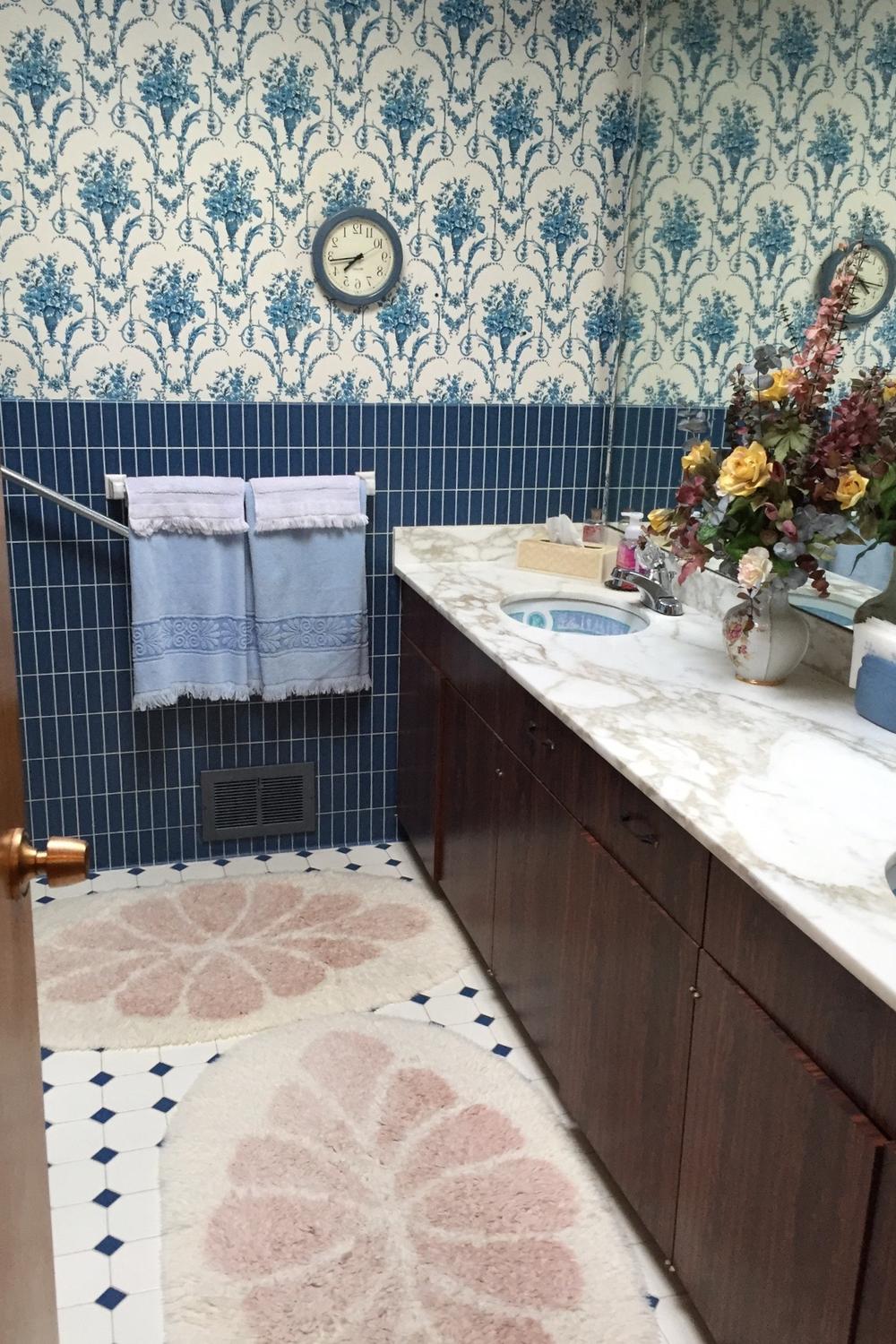A modern bohemian bathroom adorned with vintage floral wallpaper and patterned tiles.