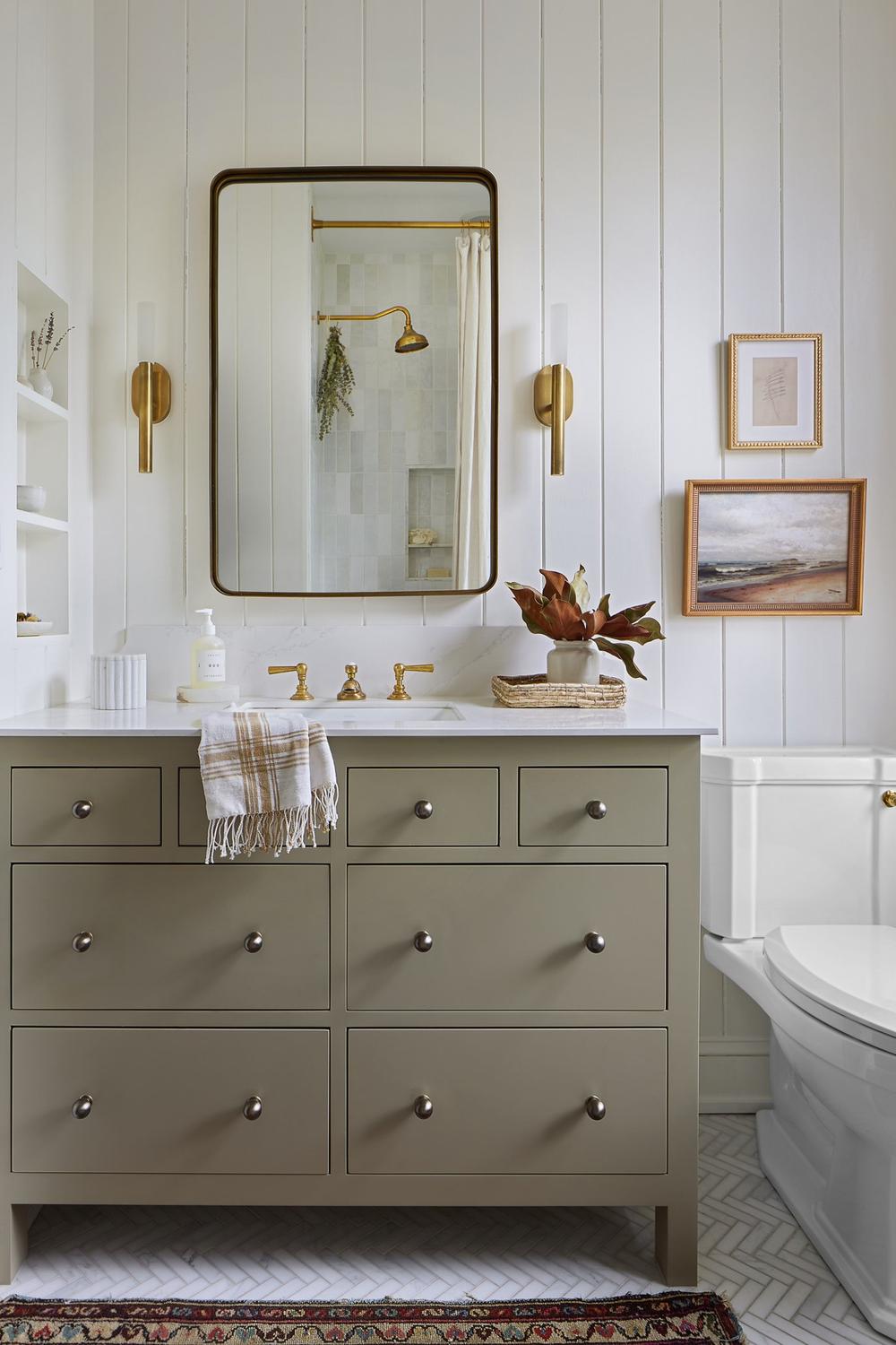 A modern cottage bathroom featuring an olive green vanity, luxurious marble countertop, and elegant fixtures.