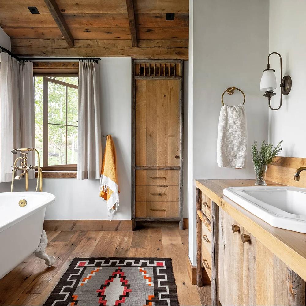 An elegant modern cottage bathroom featuring earthy tones, natural wood beams, and a freestanding tub.
