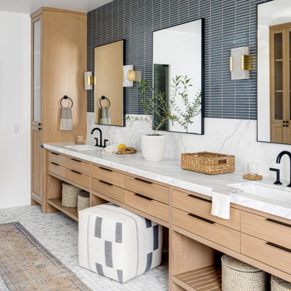 A modern cottage bathroom with a long wood vanity, elegant marble countertop, and stylish decorative elements.