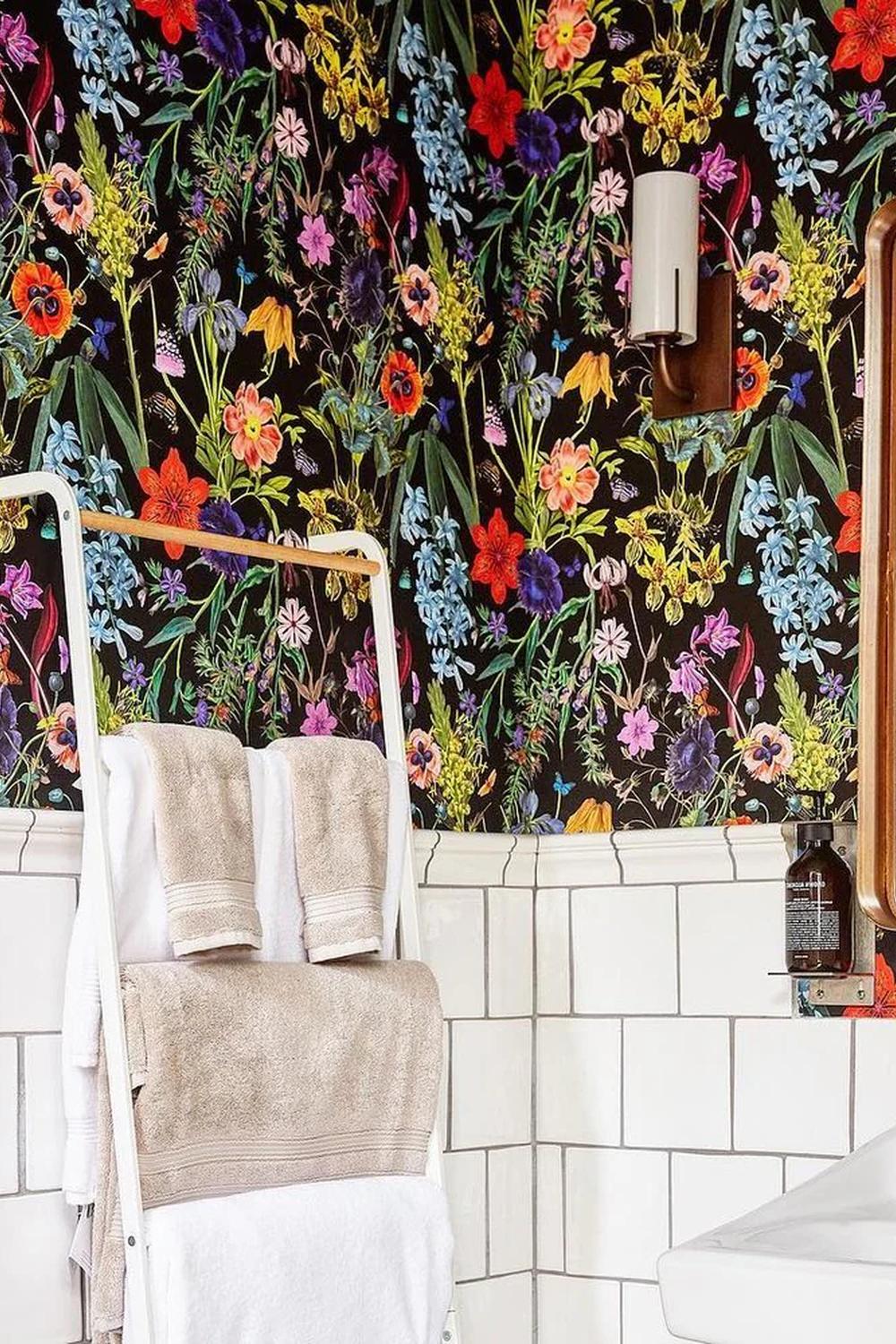 Baño con papel pintado oscuro adornado con flores vibrantes