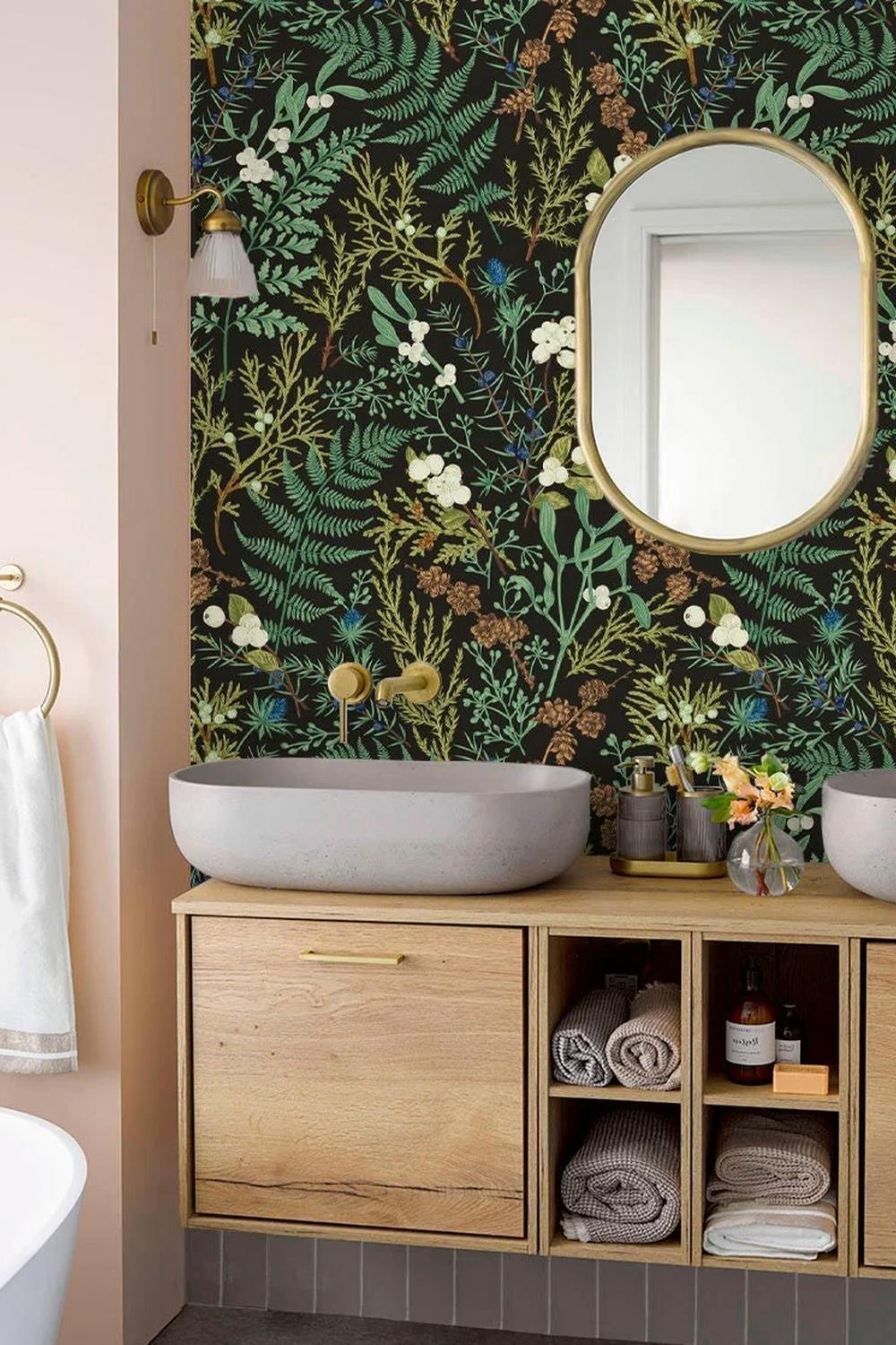 Baño con papel pintado botánico oscuro y mueble ligero de madera