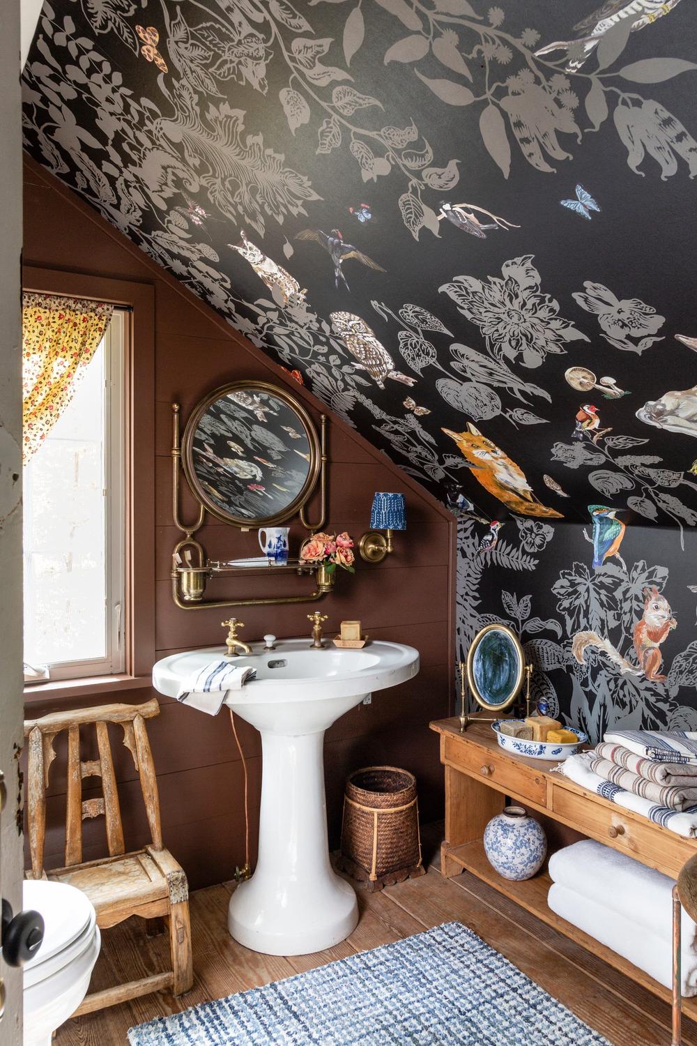 Baño vintage con papel pintado oscuro y lavabo pedestal blanco