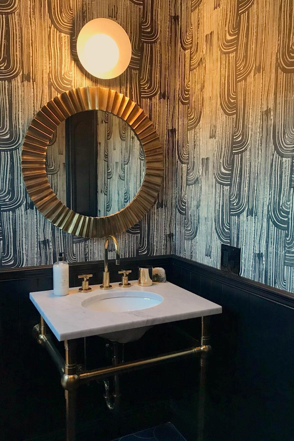 Baño con papel pintado geométrico contrastante y espejo decorativo