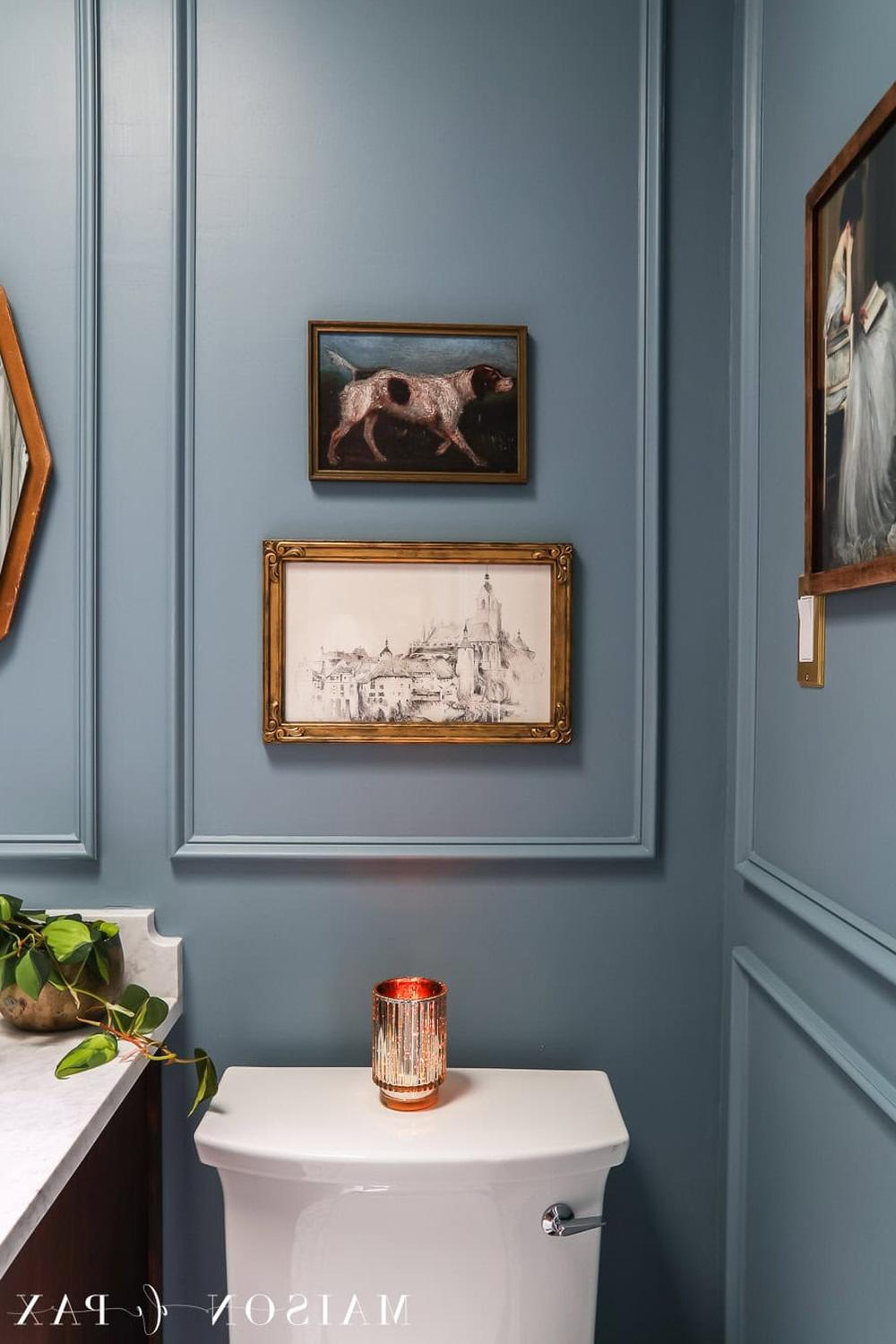 A moody blue bathroom featuring contrasting panels and playful artwork.