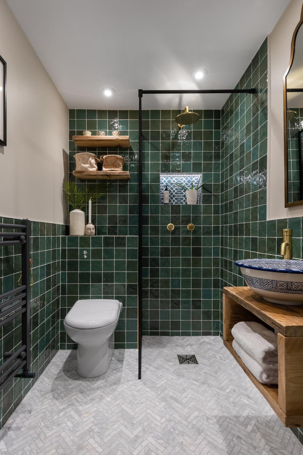 Moroccan bathroom showcasing deep green tiles and rustic wooden vanity